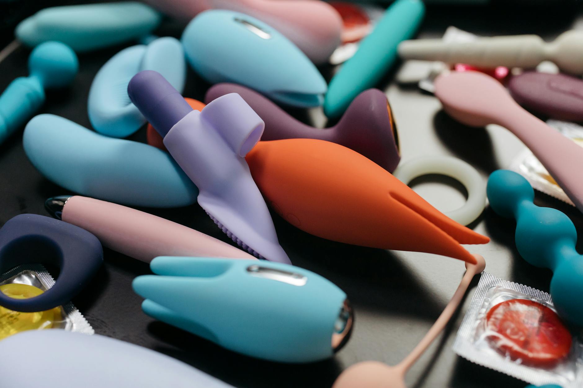 Woman with eyeglasses holding blue and pink silicone vibrators thoughtfully