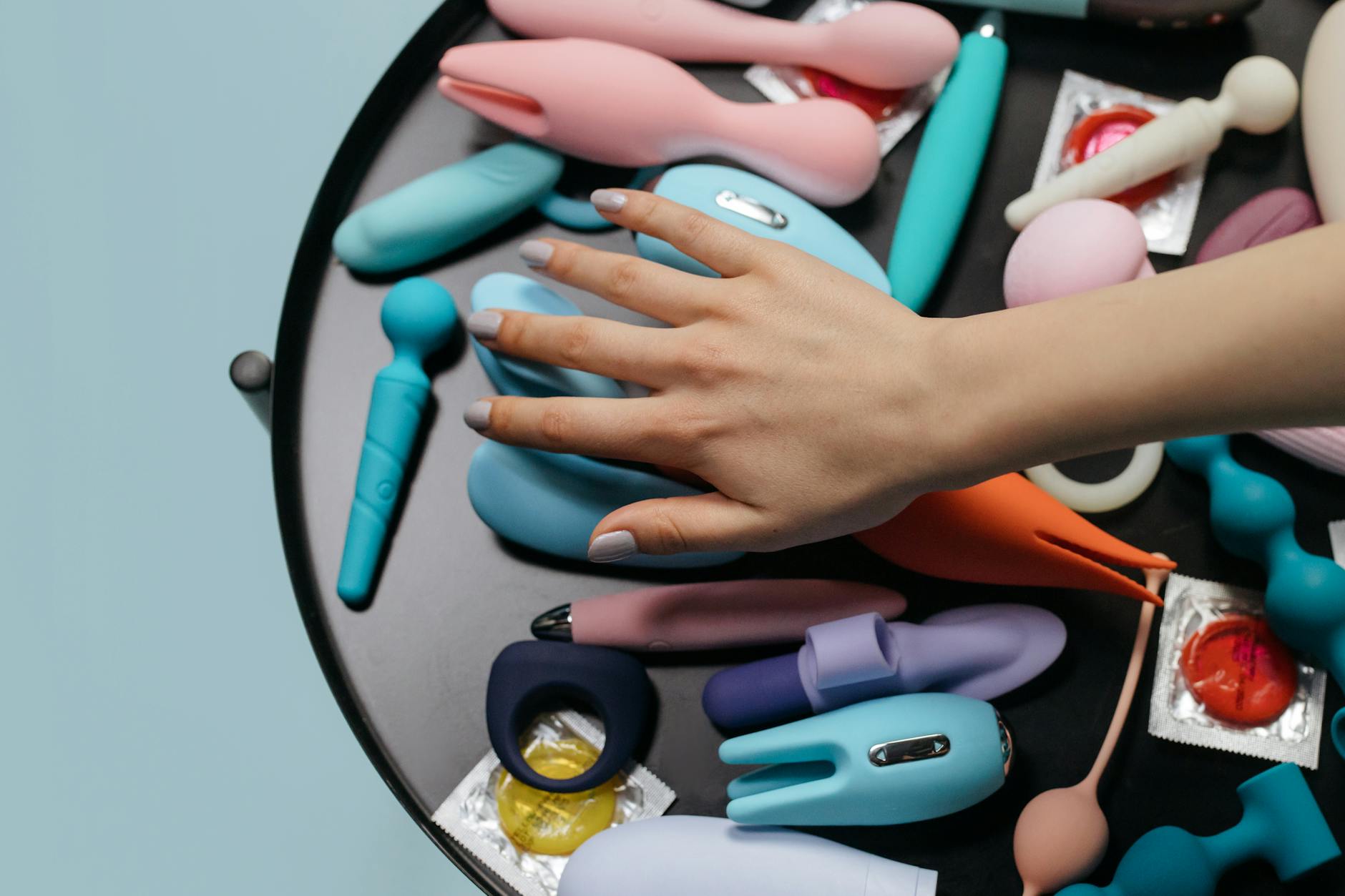 Close-up of a woman holding a lemon clitoral vibrator with art books in the background, emphasizing intimate reconnection.