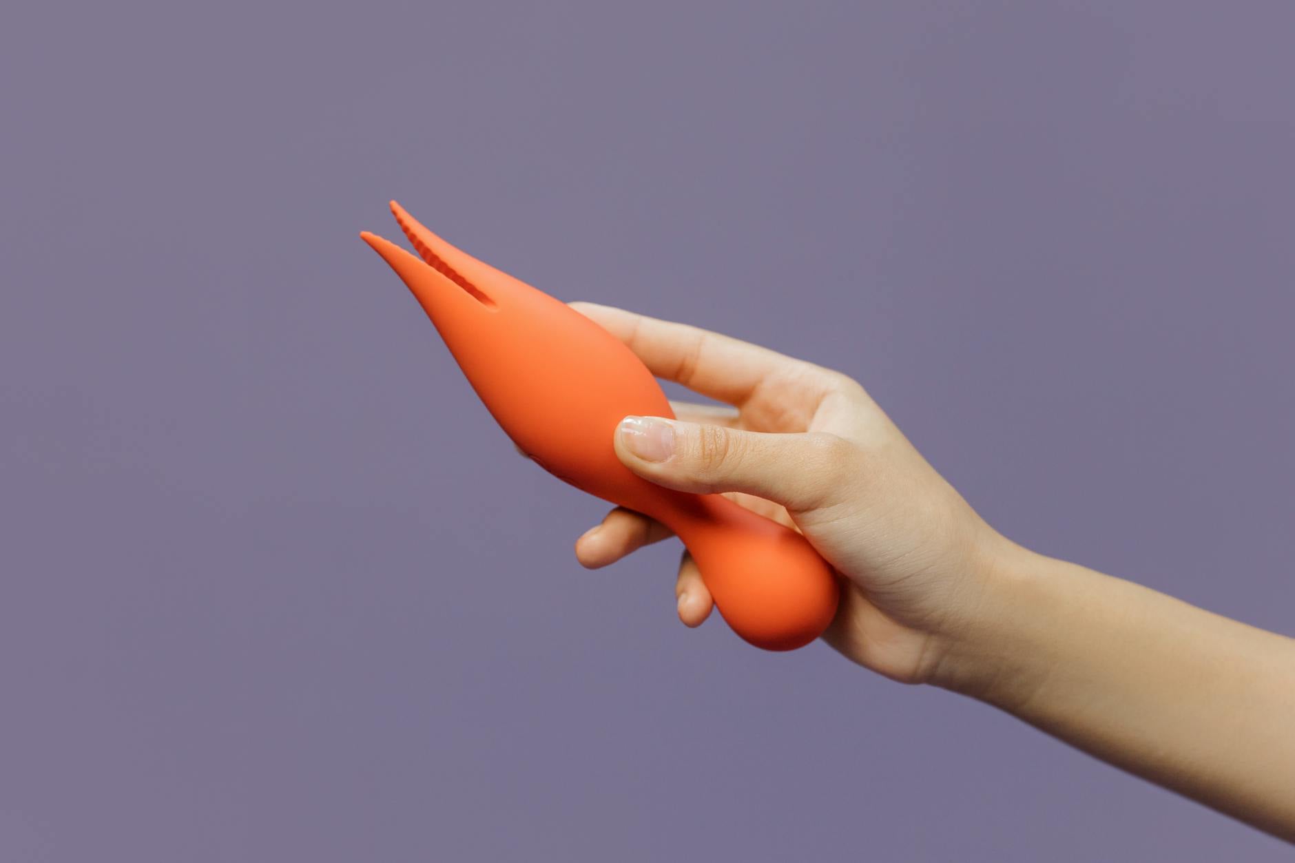 Hand holding a vibrator against a minimalistic purple backdrop, representing modern intimacy and new partnership.