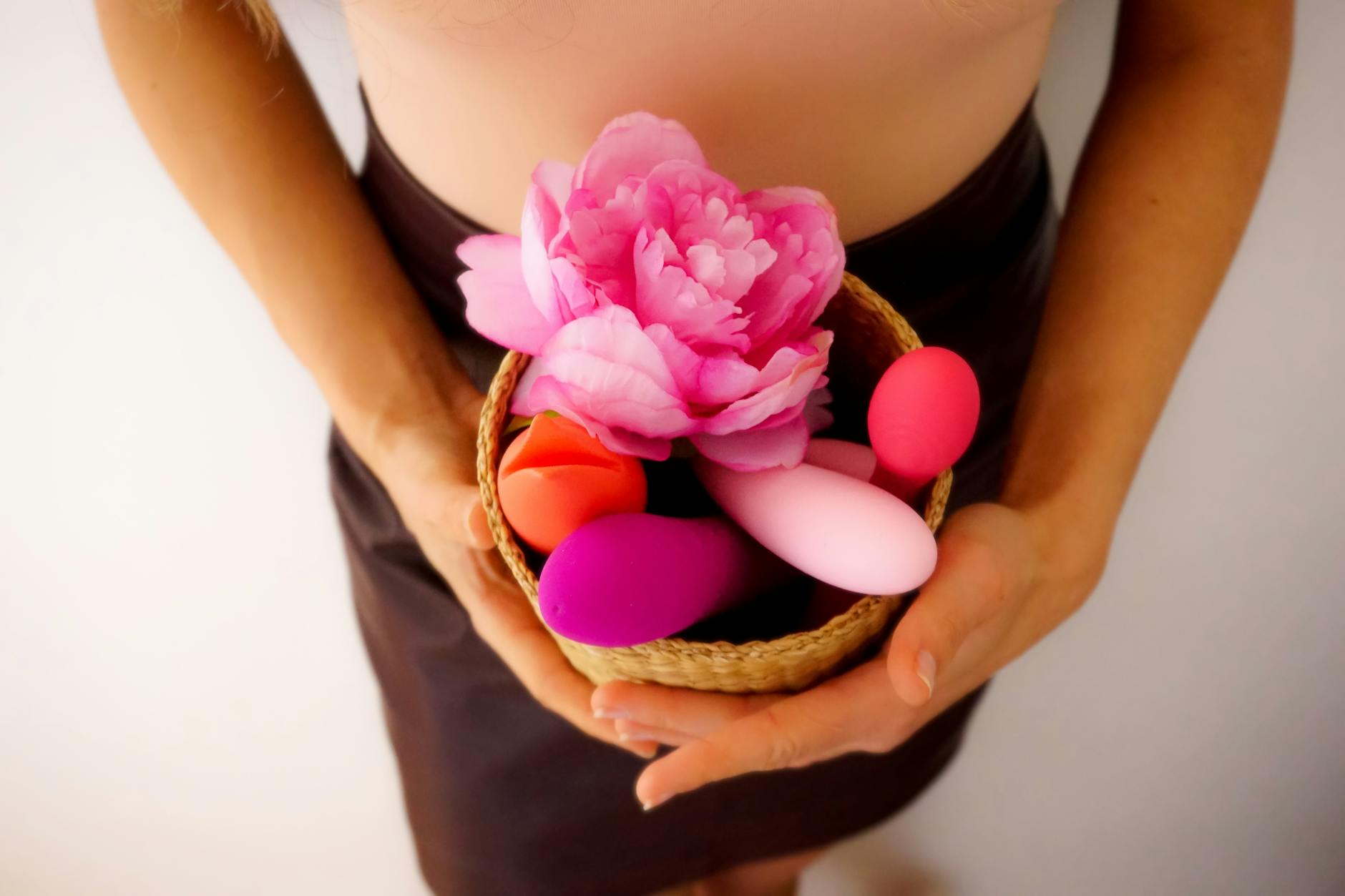 Woman holding blue and pink silicone vibrators in a contemplative manner